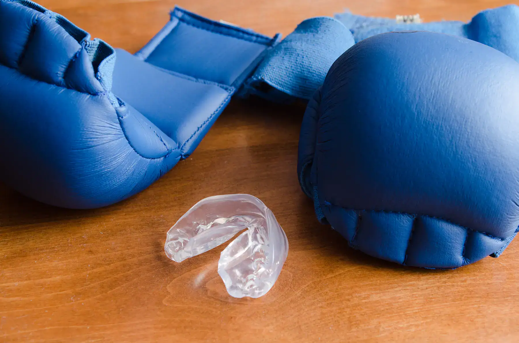 zahnschutz-sport-mundschutz Zahnschutz für den Sport - Mundschutz, Sportmundschutz, transparenter Zahnschutz zwischen zwei blauen Boxhandschuhen