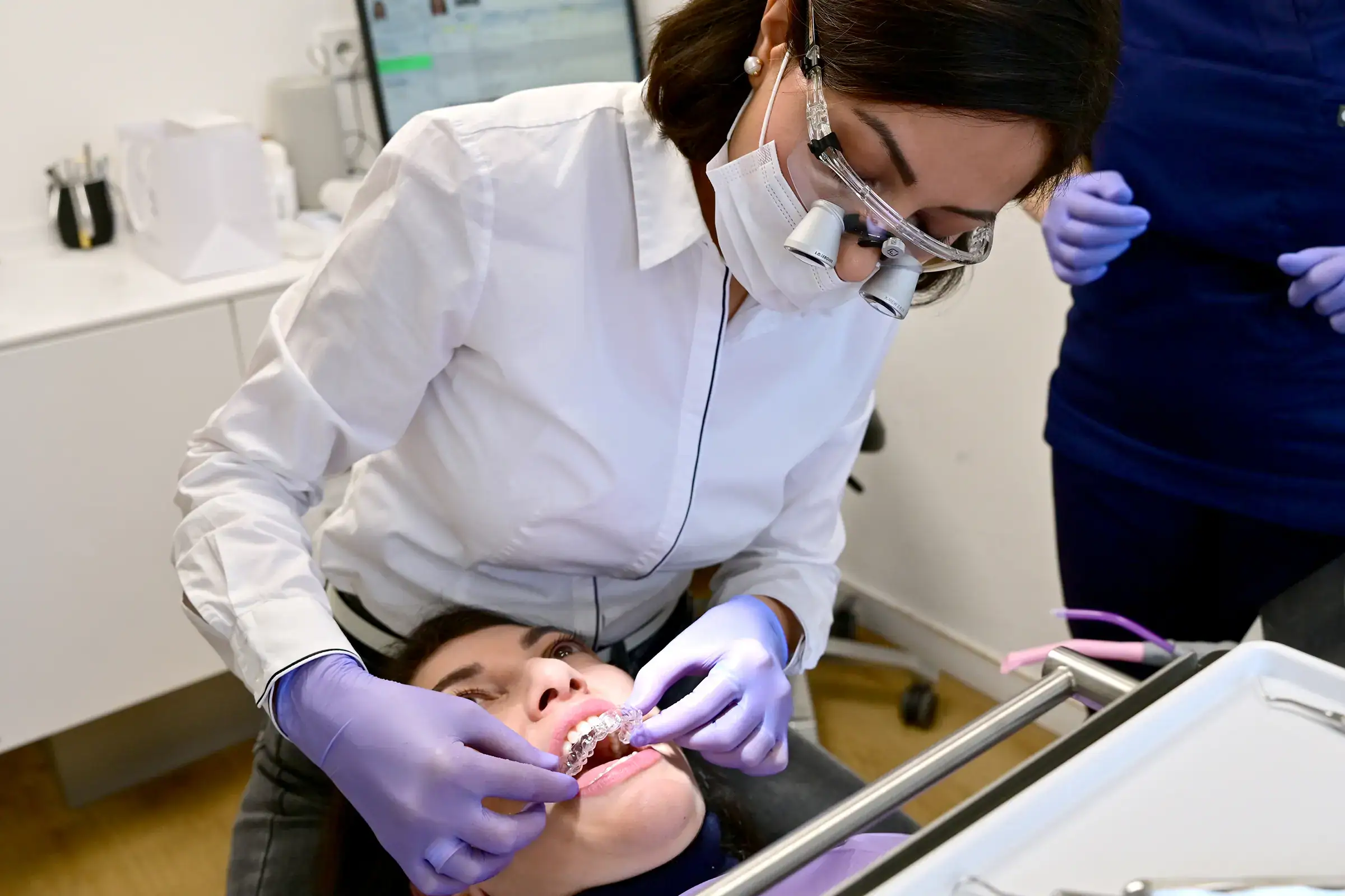 Invisalign Köln – Frau Dr. Wymar – Kieferorthopäde Köln Zahnfreude – setzt die Zahnschienen ein.